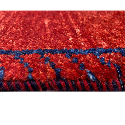 Detail: red Gabbeh runner rug with a blue decorative border and fringes