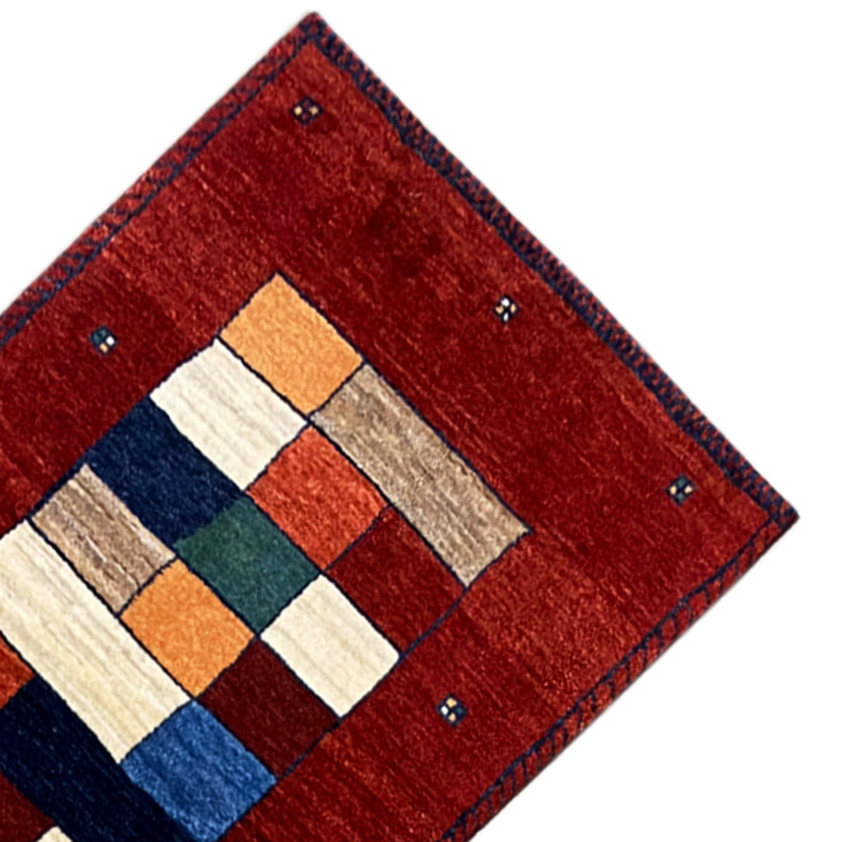 Corner detail: red Gabbeh runner rug with a central square pattern and blue border