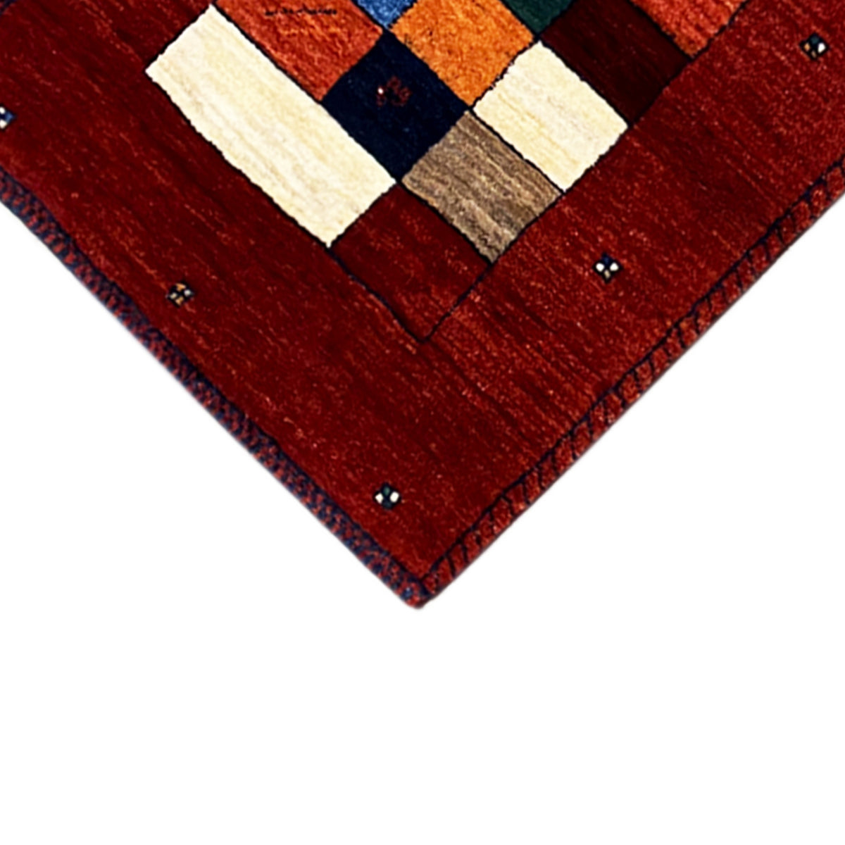 Corner detail of the red Gabbeh runner rug with a patchwork center and blue accents