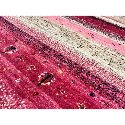Gabbeh runner rug detail: pink area with dark and colorful accents