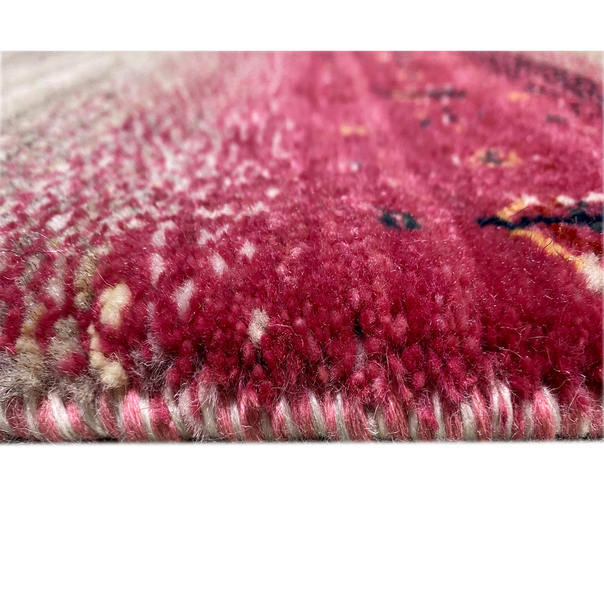 Close-up of a Gabbeh rug runner with a pink and beige pile along the edge