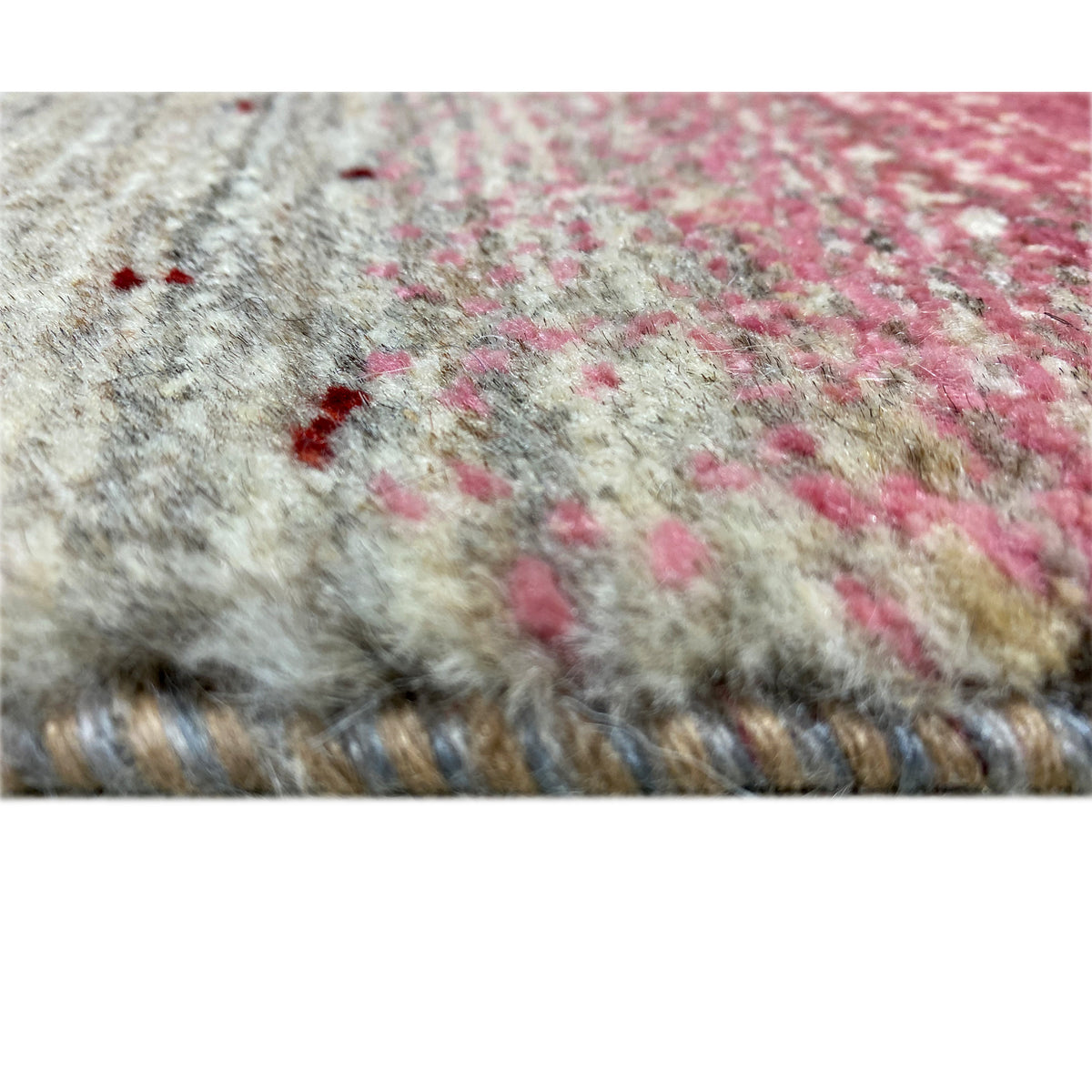 Close-up of Gabbeh fabric: beige yarn with pink flecks and colorful embellishments