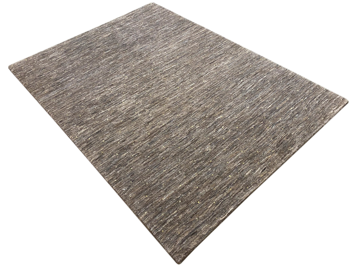 Rug detail: diagonally oriented, mottled short-pile surface in gray and beige.