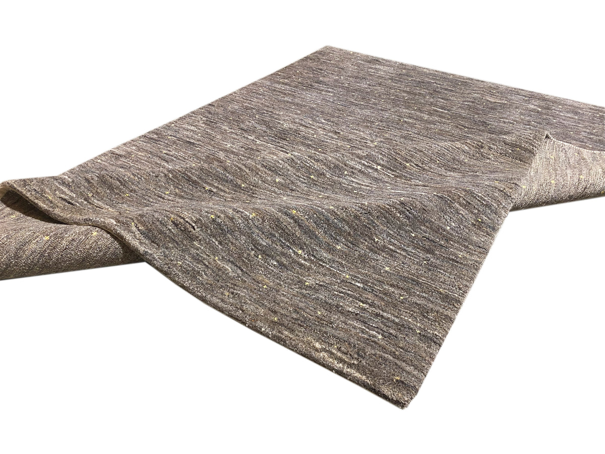 Rolled-up rug appearance: mottled gray/beige short-pile surface with fine speckles.