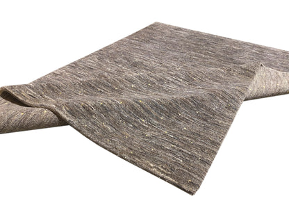 Rolled-up rug appearance: mottled gray/beige short-pile surface with fine speckles.