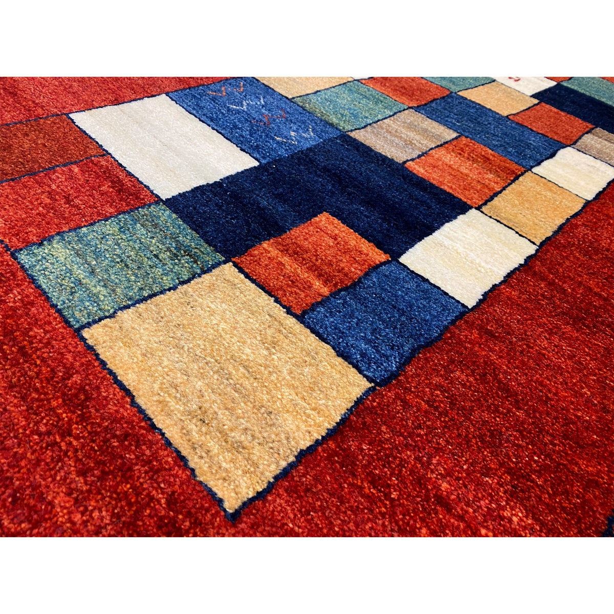 Close-up of a Gabbeh rug runner: red surface with colorful tiles in blue, green, and beige.