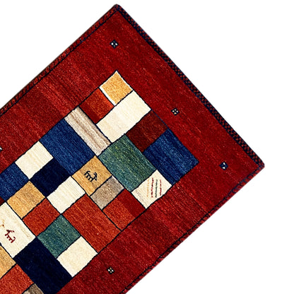 Gabbeh runner rug corner in view: red background with white and blue tiles.