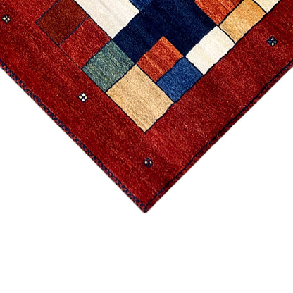 Gabbeh rug runner corner detail: red with a square pattern in blue, green, and beige.
