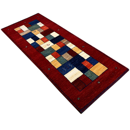 Red Gabbeh runner rug from an angled perspective with patchwork motifs in blue and beige