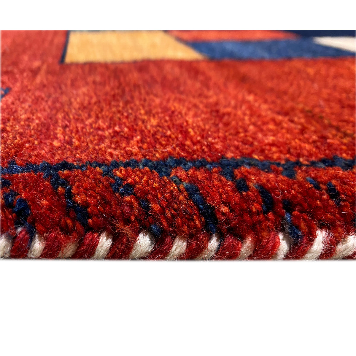 Gabbeh runner rug close-up of the edge with a blue stripe and red pile fibers