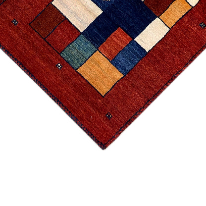 Gabbeh runner rug detail at the corner: red background with multicolored patterned elements