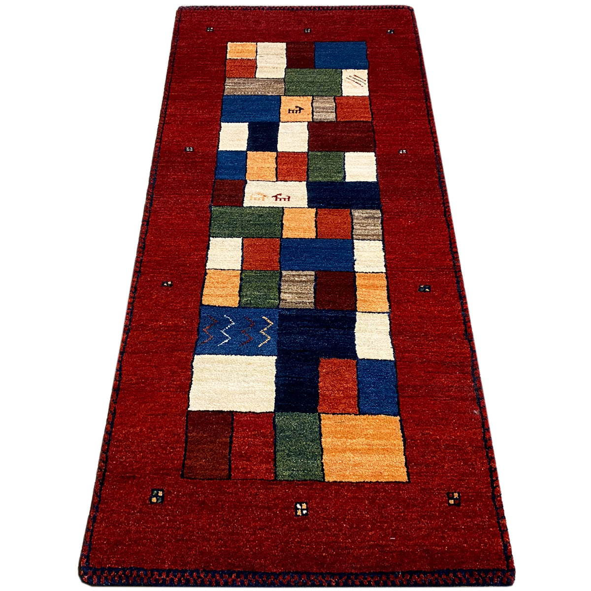 Red carpet runner with a wide border frame and multicolored patchwork pattern.