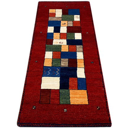 Red carpet runner with a wide border frame and multicolored patchwork pattern.