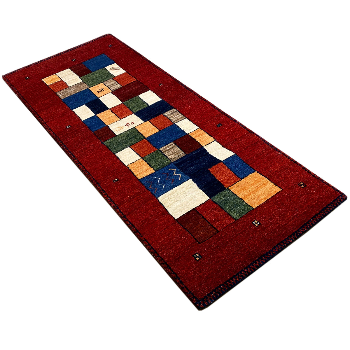 Red Gabbeh runner rug with a diagonal perspective and geometric tile pattern.