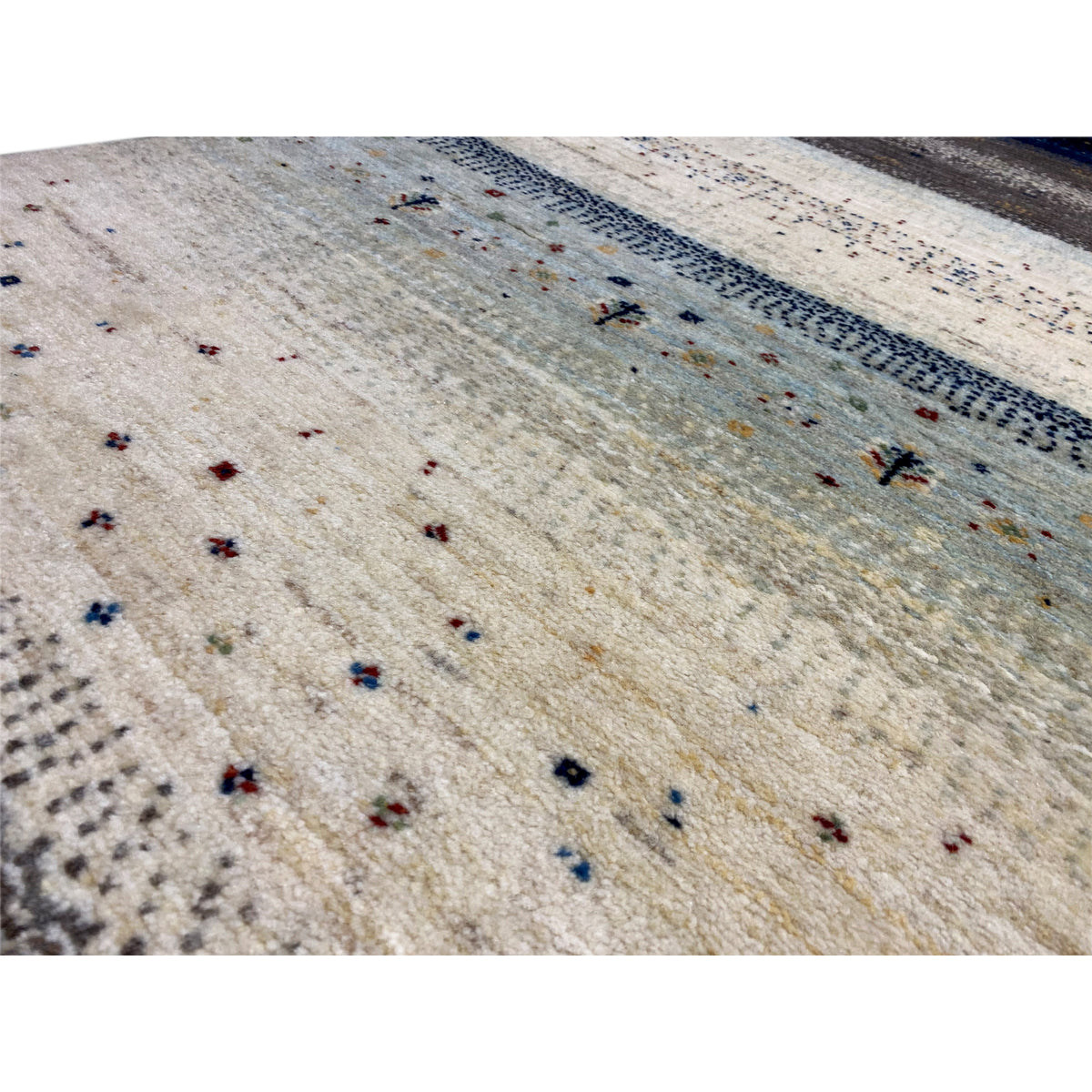 Gabbeh runner rug detail, light-colored pile with small colorful dots and blue border