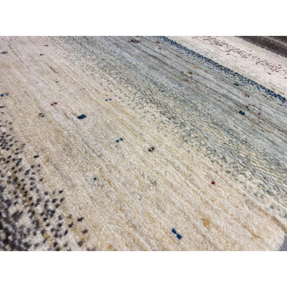 Close-up of a Gabbeh rug: light beige texture with blue and black dot accents