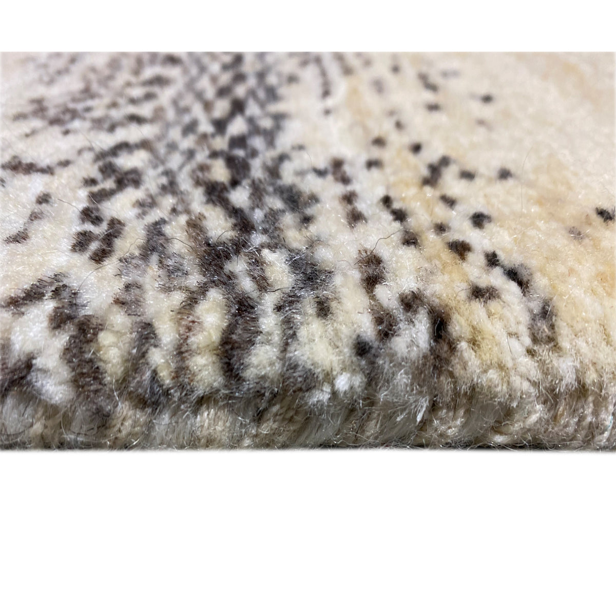 Carpet detail with a short pile and black and gray patterned spots on a beige background