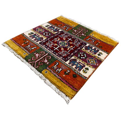 Colorful Gabbeh rug with a square medallion, green and red accents, and fringe