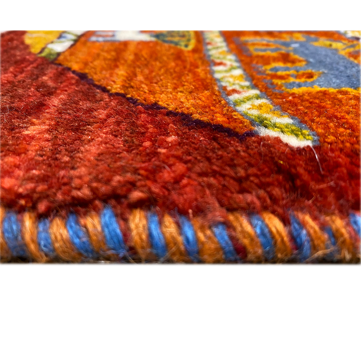 Gabbeh rug detail of the pile height and red fringes with blue stripes.