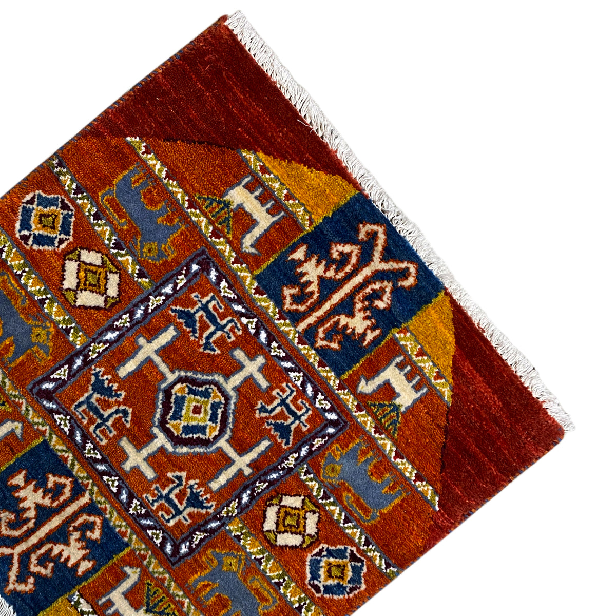 Corner of a Gabbeh rug with a dark blue field, yellow-and-white motifs, and white fringes.