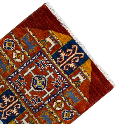Corner of a Gabbeh rug with a dark blue field, yellow-and-white motifs, and white fringes.