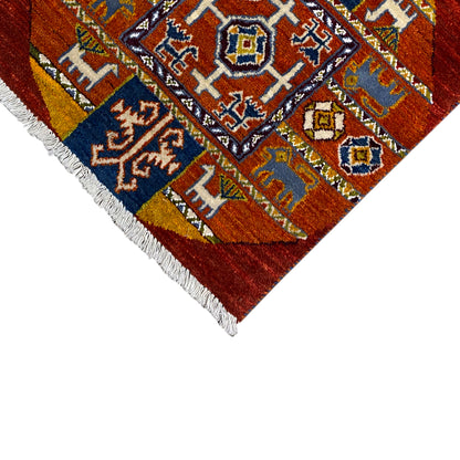 Gabbeh rug edge detail: geometric motifs in blue, orange, and white, fringes.