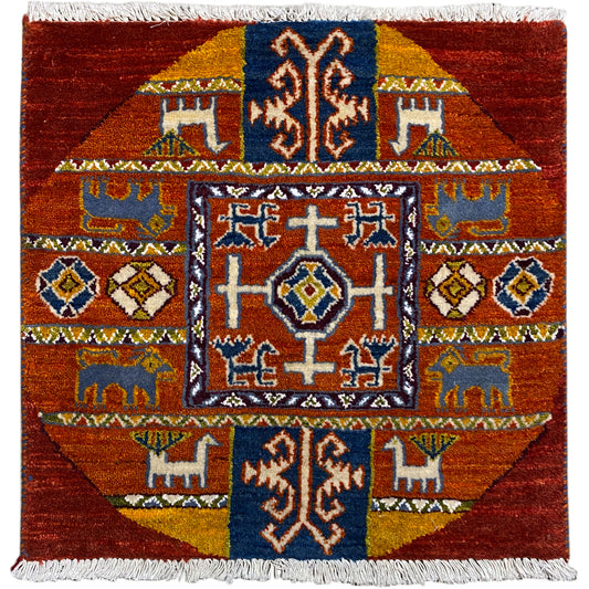 Gabbeh rug with a red background and blue and yellow ornaments, fringes along the edges.