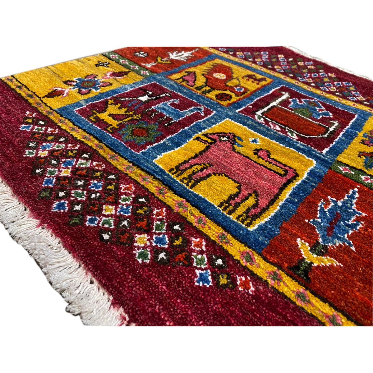 Gabbeh rug detail: burgundy pile with colorful squares, animal motifs, fringe