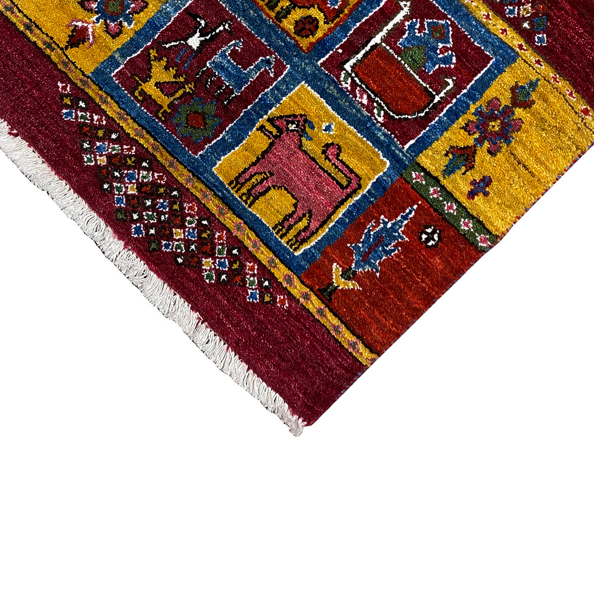 Gabbeh rug corner: yellow-blue pattern on a burgundy background, white fringes