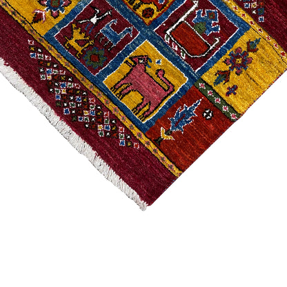 Gabbeh rug corner: yellow-blue pattern on a burgundy background, white fringes