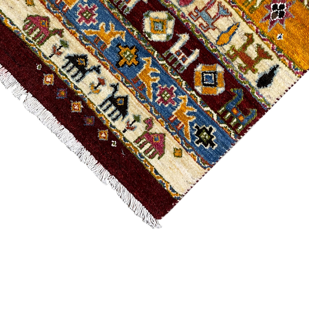 Corner of a Gabbeh rug with colorful ornaments, a dense weave, and white fringes.