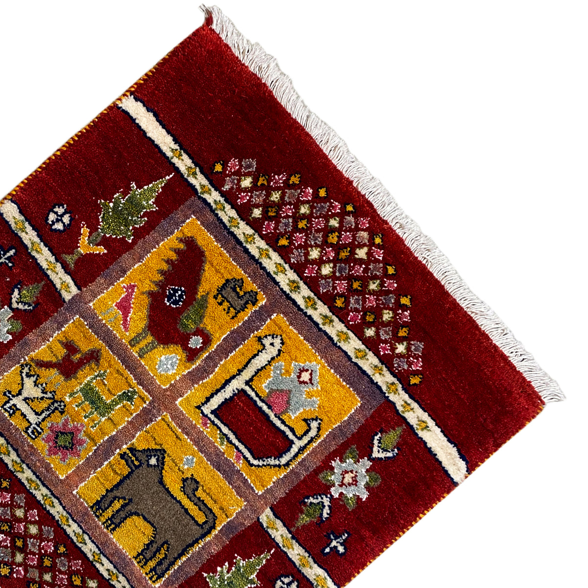 Gabbeh Lori rug detail at the edge: red pile, striped border band, and fringes