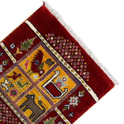 Gabbeh Lori rug detail at the edge: red pile, striped border band, and fringes