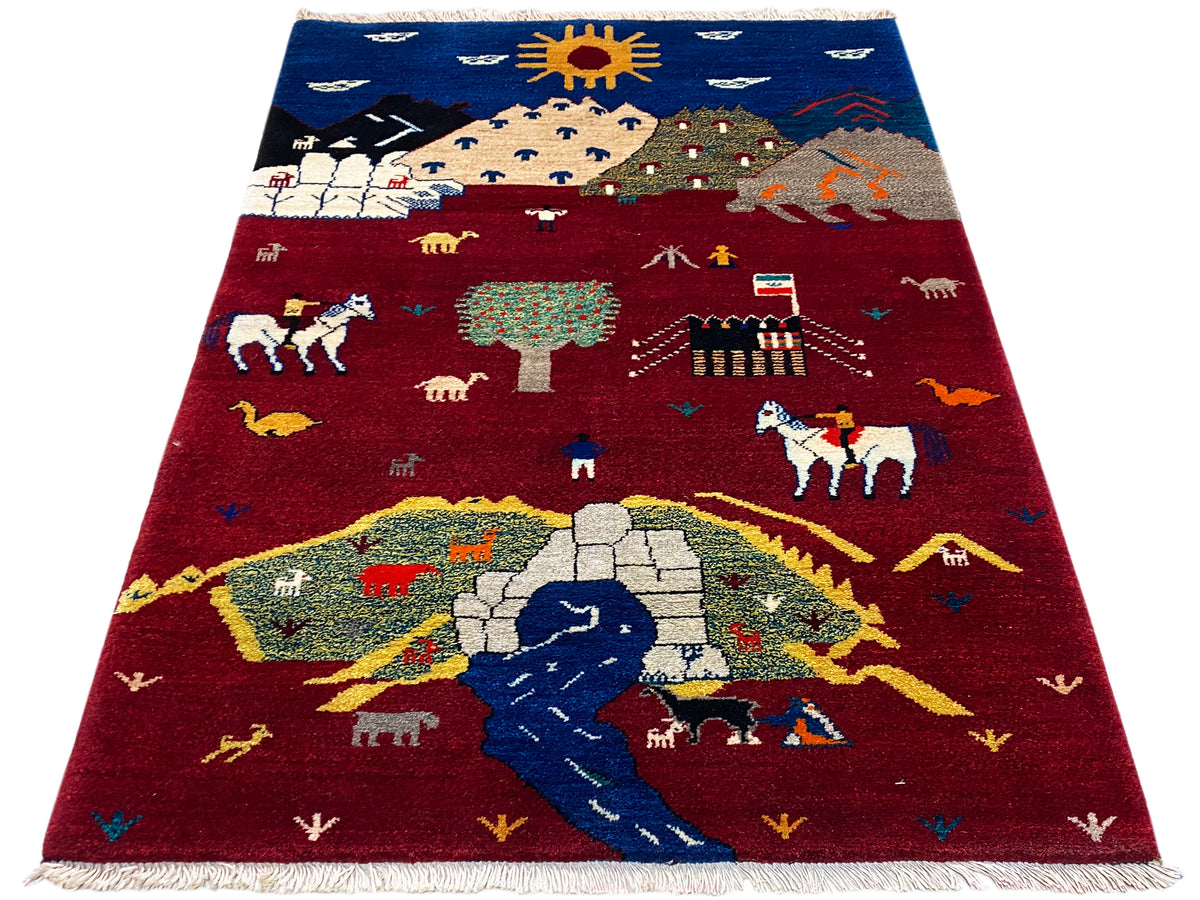 Gabbeh Luri rug in red and blue with landscape and animal motifs, fringes
