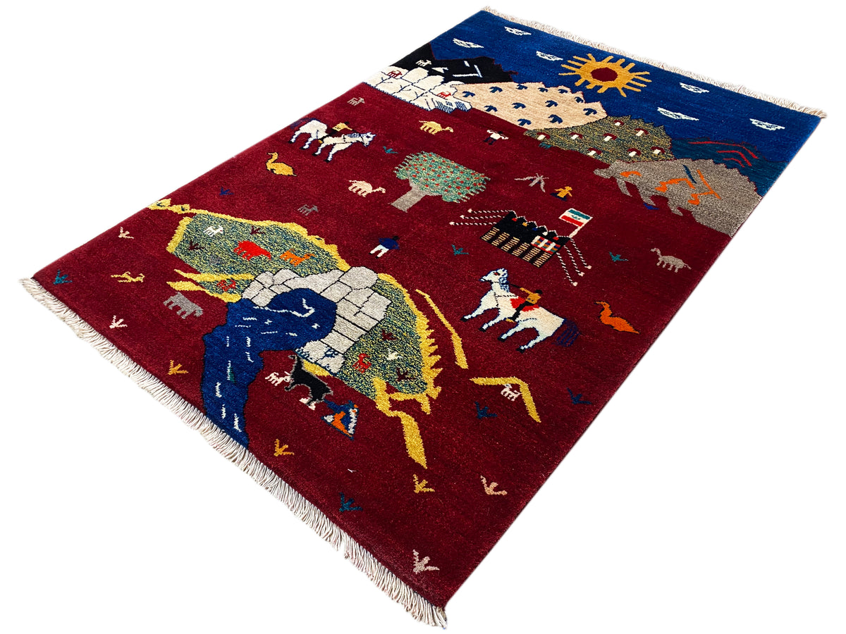 Gabbeh-Luri rug at an angle, red field with figures, horses, and colorful bands, fringes