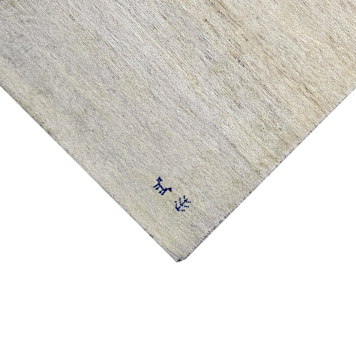Close-up of a carpet edge: light beige pile with a dark blue animal motif