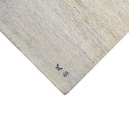 Close-up of a carpet edge: light beige pile with a dark blue animal motif