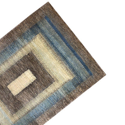 Gabbeh rug corner with a dark border and blue stripe