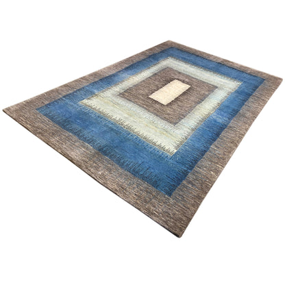 Gabbeh rug in the corner of the room, geometric border in blue, brown, and cream