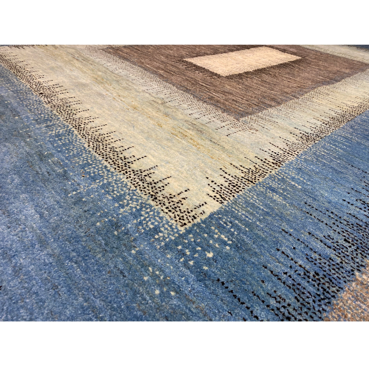 Close-up of the Gabbeh rug: dense pile with a blue field and brown border pattern