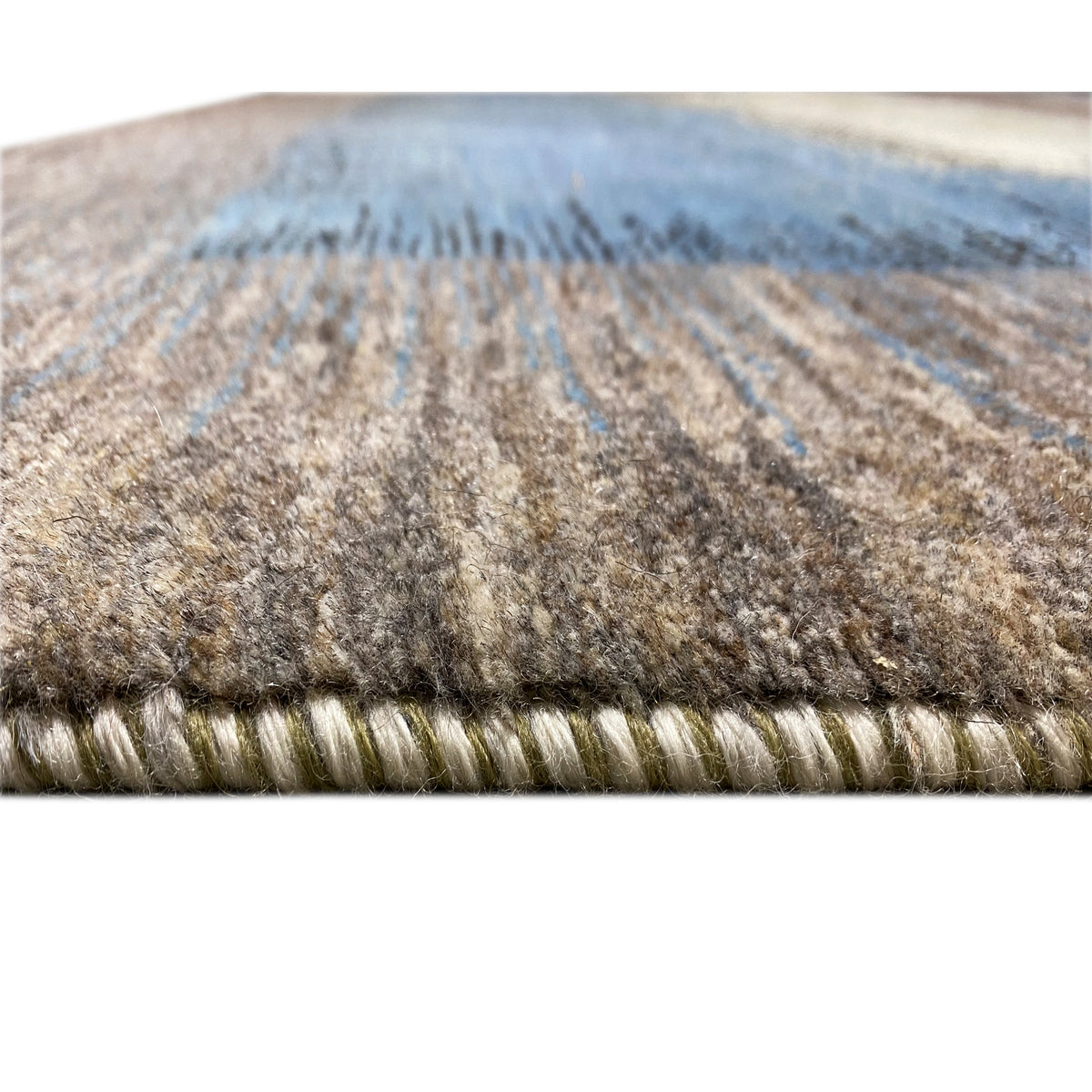 Close-up of the carpet edge: multicolored pile strip in brown, cream, and blue tones