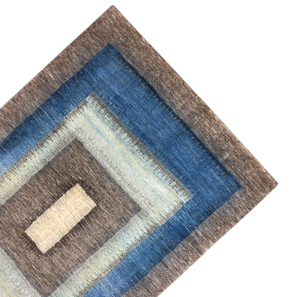 Gabbeh rug corner with blue decorative band, cream-colored rectangle, and brown background