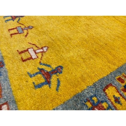 Close-up: Gabbeh runner with a yellow field and colorful figures in a border pattern