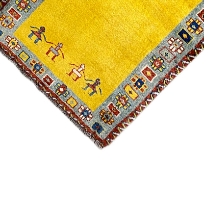 Corner of the Gabbeh runner: yellow rug with decorative border and fringes