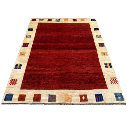Gabbeh rug, broad red area with a cream-colored border and small block patterns