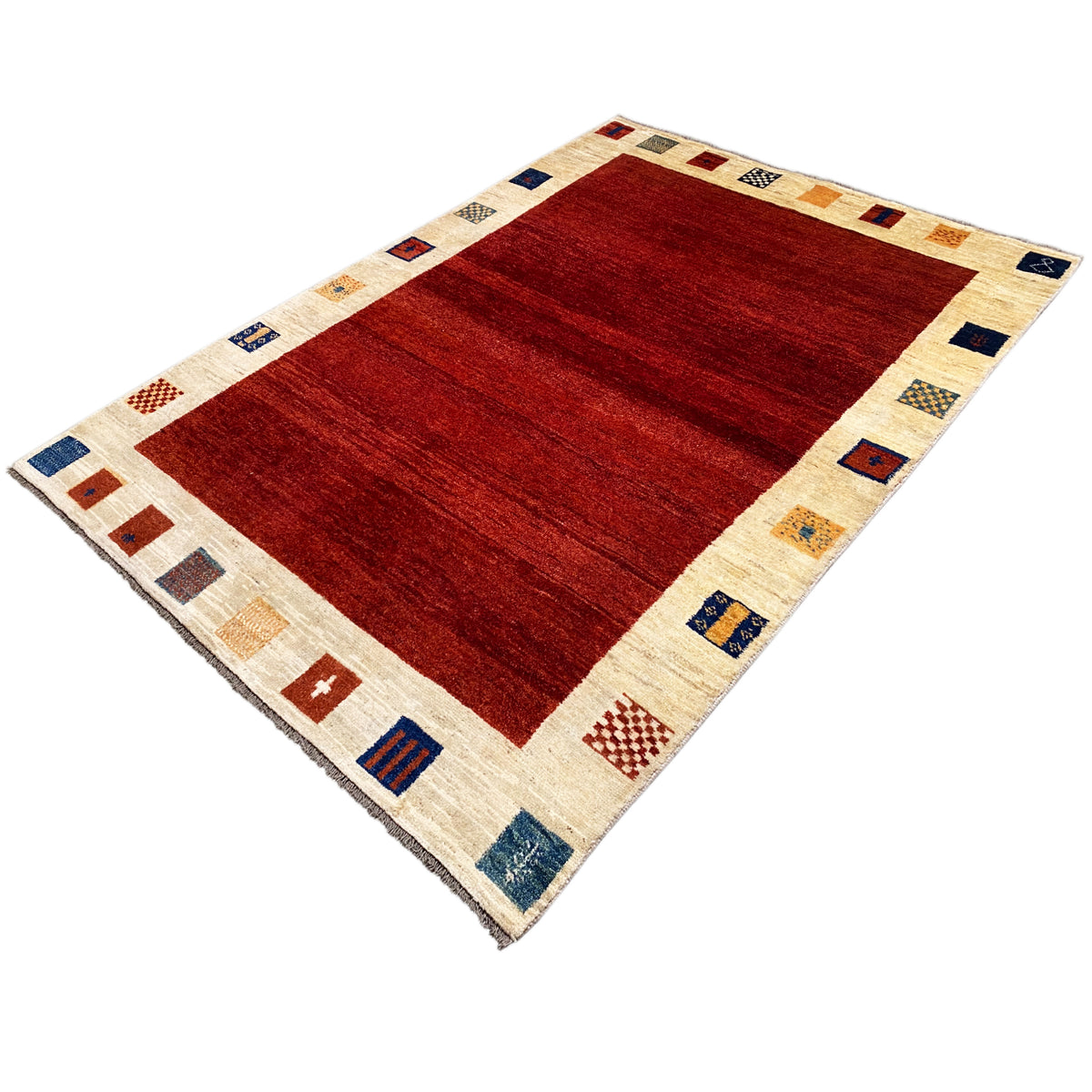 Gabbeh rug at a three-quarter angle: dark red field, cream-colored border with colorful motifs