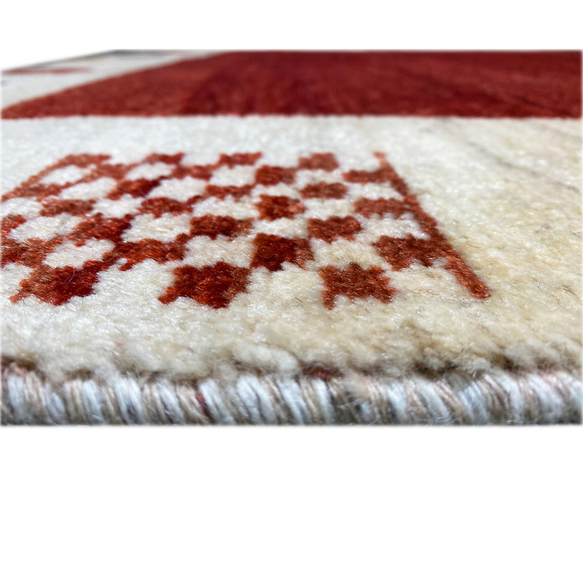 Gabbeh rug detail at the edge: cream-colored pile, red patterned area, and fringes