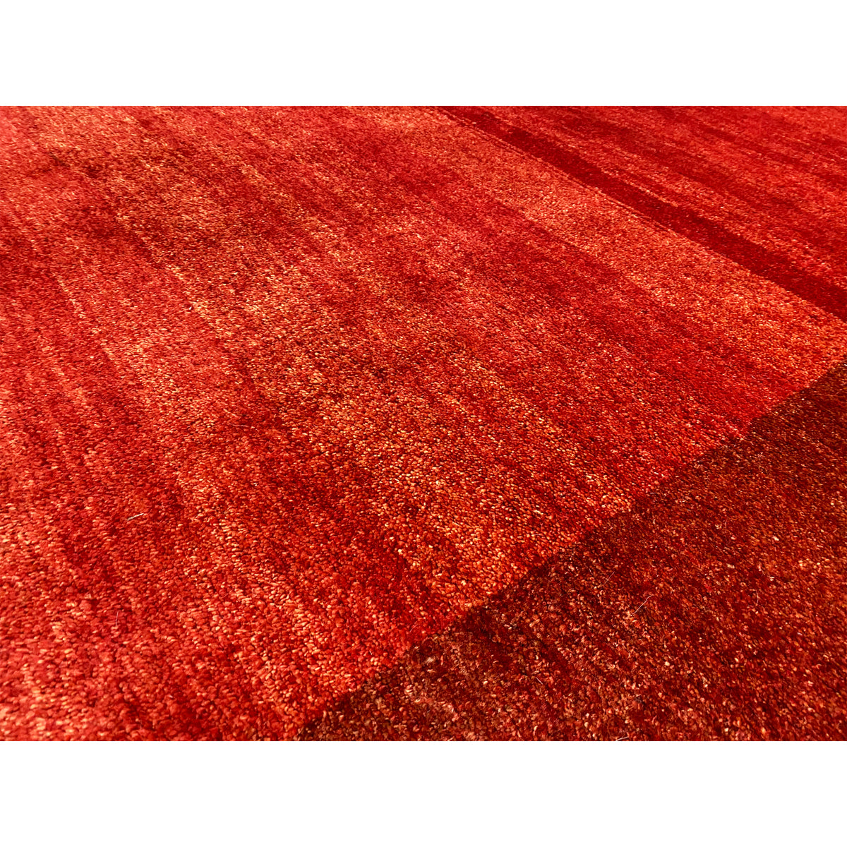 Close-up of Gabbeh rug: red, mottled pile with a textured surface