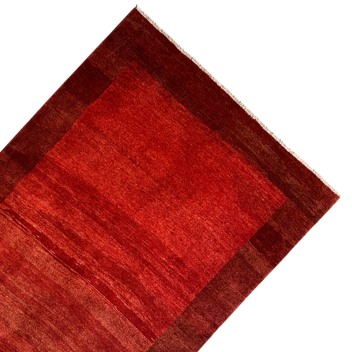 Gabbeh rug with a red central section and brown border, corner view