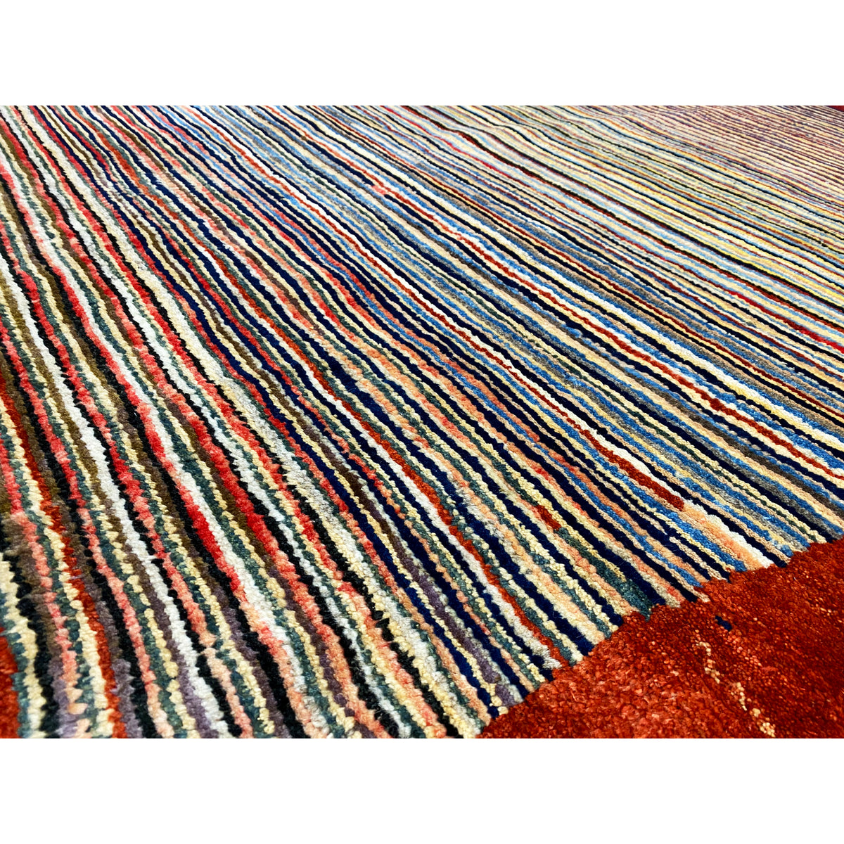 Close-up: dense striped pattern in shades of blue, red, and yellow on a light background